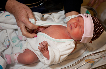 A newly born baby being kept warm in the hospital nursery.